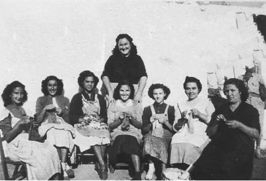 Un grup de dones assegudes al carrer teixint